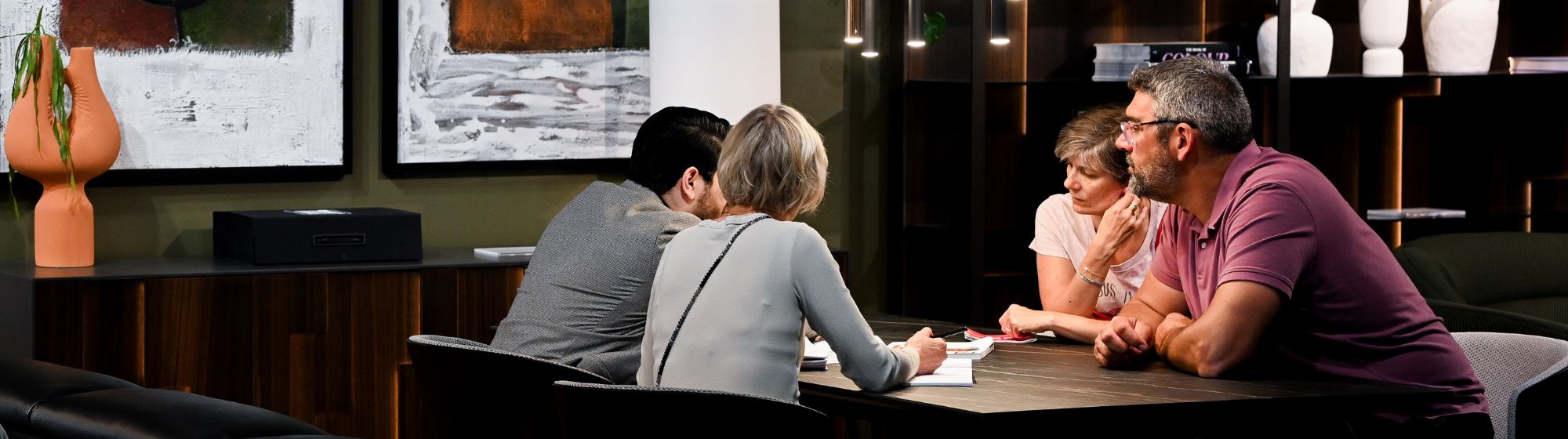 Quatre personnes en discussion autour d'une table dans un showroom de mobilier