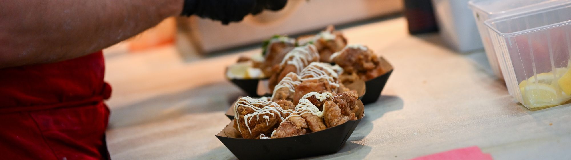 Un cuisinier d’un stand de la Foire de Paris dresse des portions de poulet frit nappé de sauce