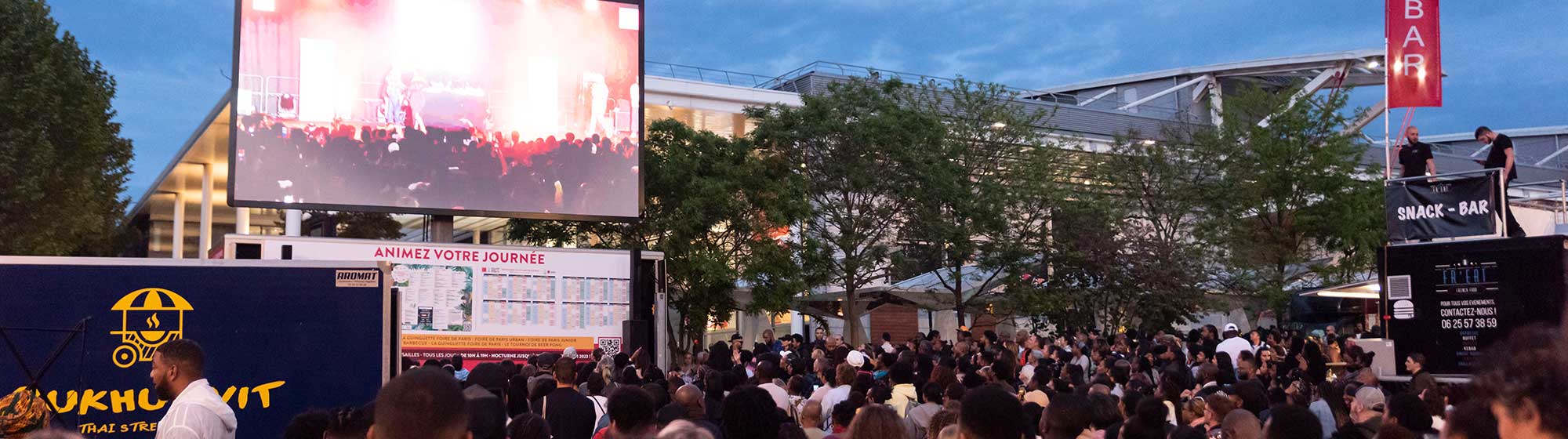 visiteurs suivant le concert de la nocturne à l'extérieur, dans le parc d'expositions