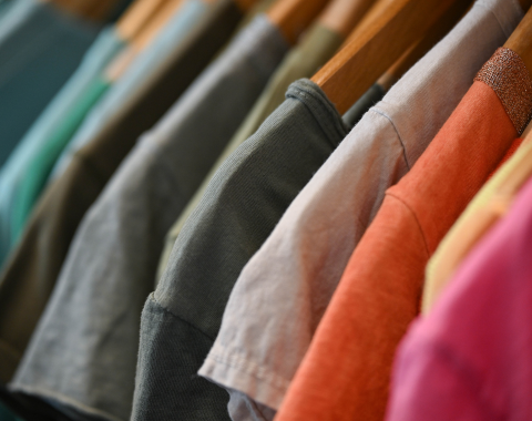 tee-shirts classés par couleurs sur des jolis ceintres en bois