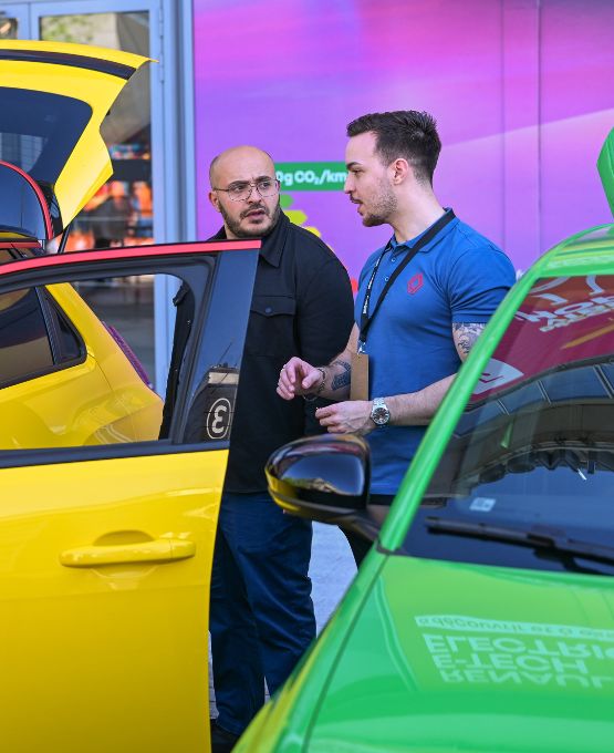 Conseiller automobile présentant une voiture électrique jaune à un visiteur lors de la Foire de Paris, exposition de véhicules innovants.