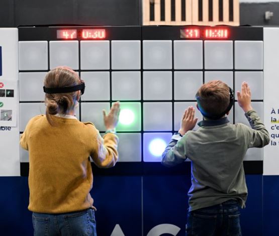 Deux enfants participent à un jeu de réflexes lumineux sur le stand de prévention de la MACIF