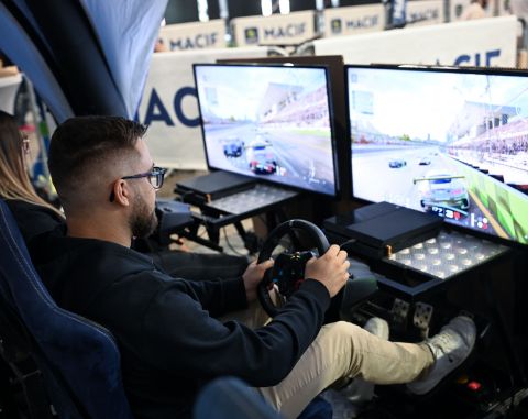 Homme jouant à un simulateur de course automobile avec double écran lors d’un salon