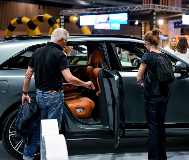 Visiteurs découvrant l’intérieur d’un SUV haut de gamme au salon de l’auto à Foire de Paris