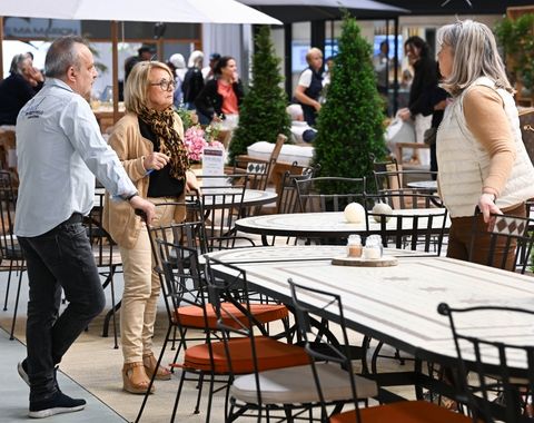 Visiteurs échangeant autour d’une table de jardin élégante sur un stand extérieur à foire de paris