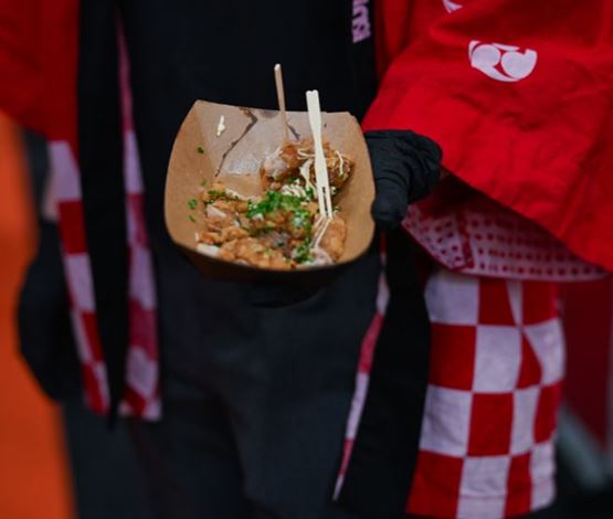 Dégustation de poulet frit japonais garni de sauce et de ciboulette à la Foire de Paris, servie dans un récipient éco-responsable