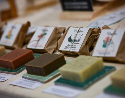 Savons artisanaux exposés sur un stand, présentés avec leurs étiquettes et emballages kraft