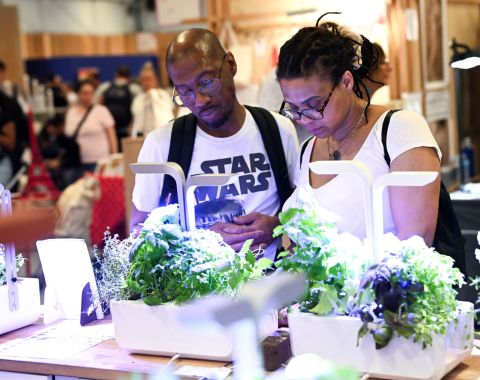 Deux visiteurs observant un système de culture de plantes en intérieur avec éclairage LED à la Foire de Paris