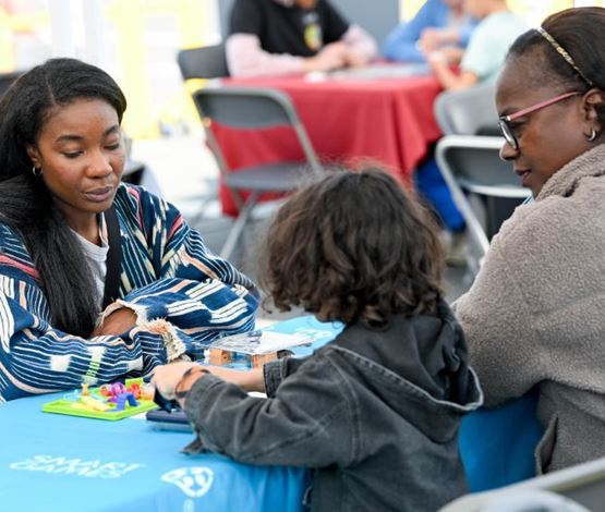 Famille jouant ensemble à un jeu de logique sur une table lors d’un événement