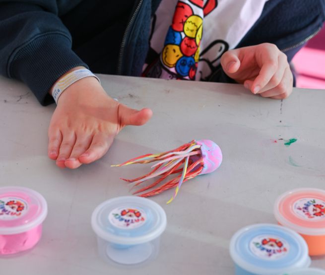 Un enfant crée une méduse colorée en pâte à modeler lors d’un atelier manuel