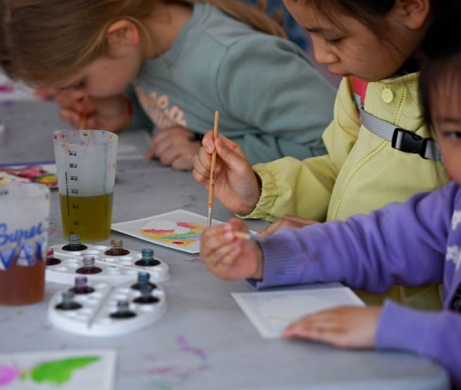Enfants concentrés en train de peindre avec des pinceaux lors d’un atelier artistique