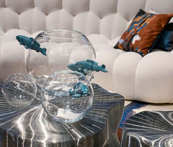 objets design en verre soufflé avec poissons bleus, sur table métallique face à un canapé
