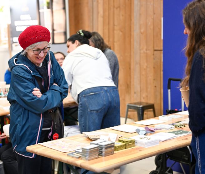 visiteuse découvrant des créations papier et objets faits main sur stand world in paris