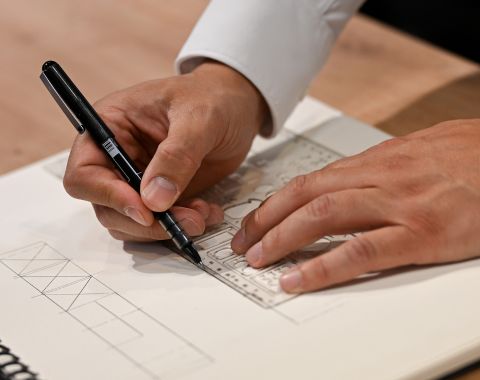 Architecte dessinant un plan détaillé avec un stylo sur un carnet lors d’une consultation à foire de paris