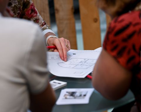 Professionnels discutant des détails d’un plan architectural lors d’une rencontre au stand architecture à foire de paris