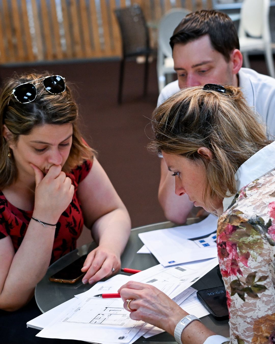 Visiteurs examinant un plan architectural avec un expert lors d’une consultation au stand d’architecture à foire de paris