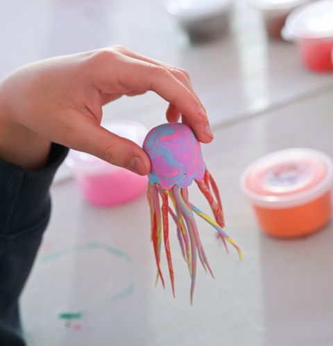 Enfant tenant une petite méduse en pâte à modeler colorée