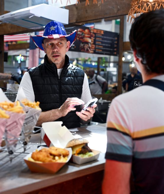 Stand de restauration à la Foire de Paris avec un vendeur portant un chapeau bleu à étoiles