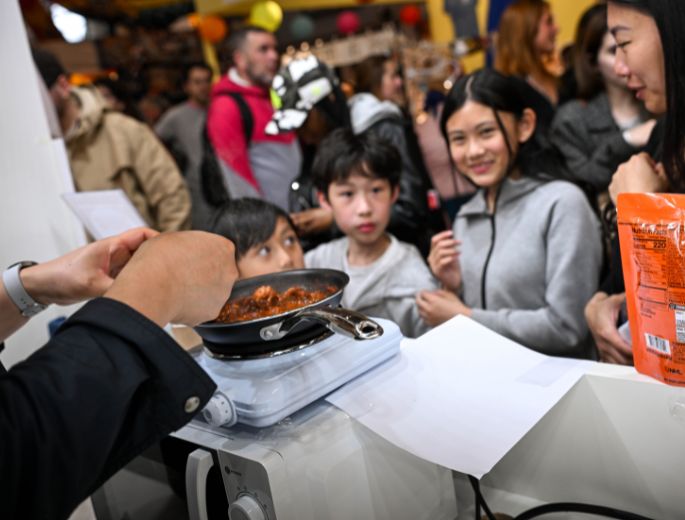 Démonstration culinaire à la Foire de Paris devant un groupe d’enfants curieux