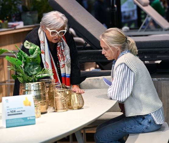 Visiteur assis à une table écoutant les conseils d'un exposant maison